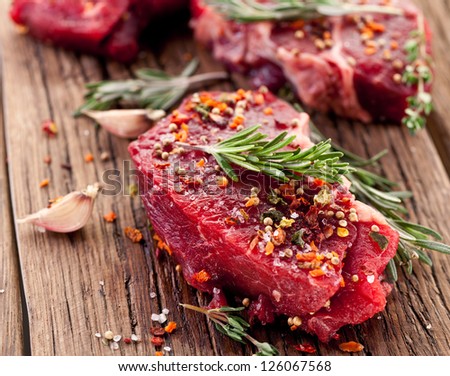 Raw beef steak on a dark wooden table.