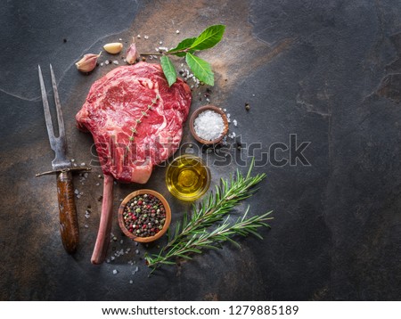 Raw  Ribeye steak or beef steak on the graphite cutting board  with herbs and spices. Top view.
