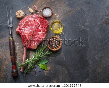 Raw  Ribeye steak or beef steak on the graphite cutting board  with herbs and spices. Top view.