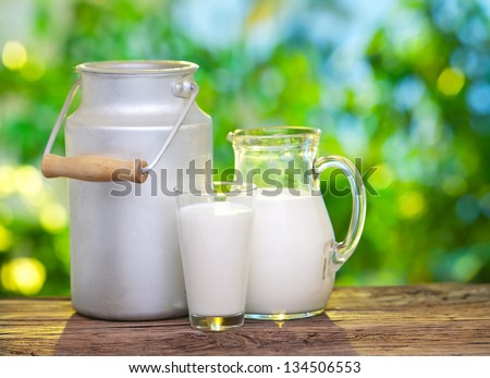 Milk In Various Dishes On The Old Wooden Table In An Outdoor Setting.