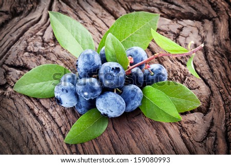 Blueberries with leaves on a wooden table. Studio isolated.