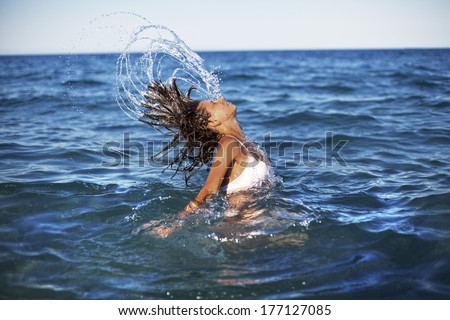 Woman splashing water with her hair in the sea.