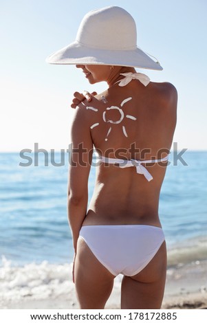 Tanning lotion in the shape of sun on woman\'s shoulder.
