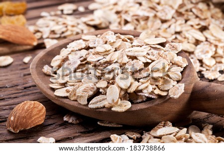 Rolled oats in the wooden spoon over old wooden table.