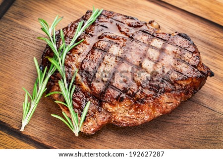 Beef steak with rosemary on a wooden table.