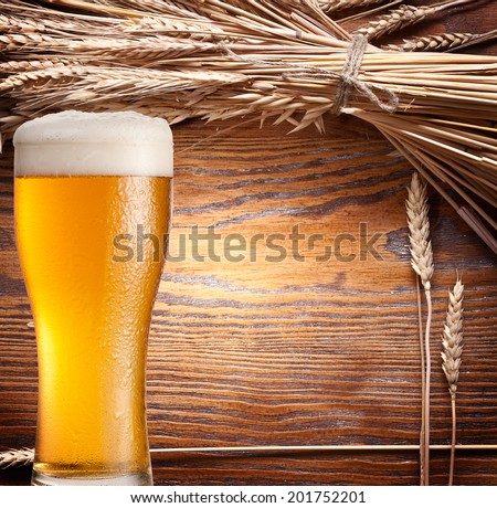 Ears of wheat & beer glass on old wooden table.