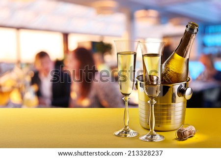 Champagne flutes and chilled bottle at the bar counter.