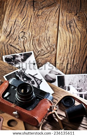 Old rangefinder camera and black-and-white photos on the old wooden table.
