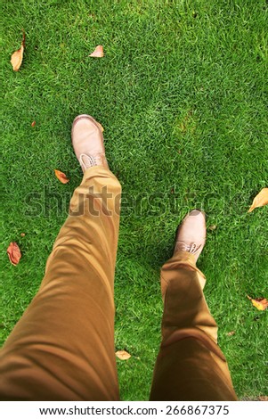 Walking in the park. Man\'s feet in shoes on the grass. Top view.