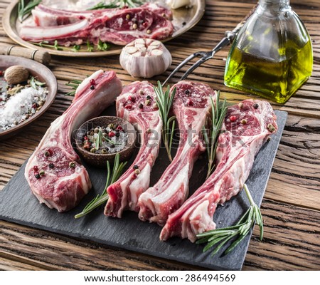 Raw lamb chops with garlic and herbs on the old wooden table.