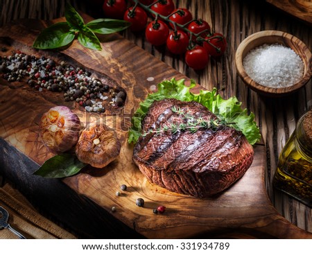 Beef steaks with spices on a wooden tray. Barbecue food.