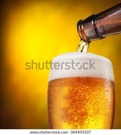 The process of pouring beer into the glass. Bright orange background.