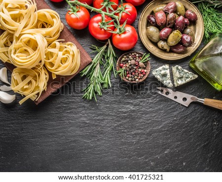 Pasta ingredients. Cherry-tomatoes, spaghetti pasta, rosemary and spices on a graphite board.