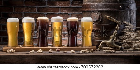 Glasses of beer and ale barrel on the wooden table. Craft brewery. Six varieties of beer.