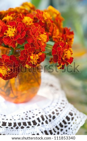 bright red flowers marigolds in a vase on a table.