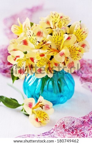 beautiful yellow flowers in a blue glass vase on a table.
