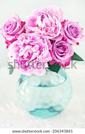 Floral composition with a pink peony and roses in a glass vase.
