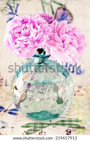 Floral composition with a peony and roses in a glass vase. Pink flowers on a colorful table .
