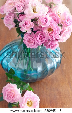 Beautiful fresh pink roses in a blue vase .vintage style ,grunge paper background.