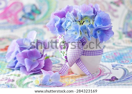 beautiful hydrangea flowers in a pot decorated with a heart on a beautiful tablecloth.