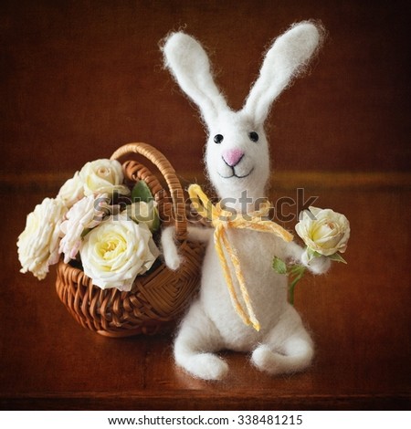 Homemade toy rabbit with a bouquet of flowers on a brown background with a texture .Felted wool toy.
