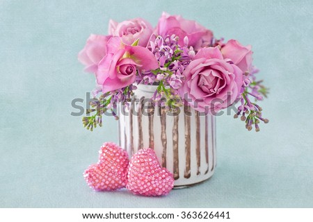 Lilacs and pink roses flowers decorated with a heart on a blue background with texture . Floral gift for a wedding or birthday.
