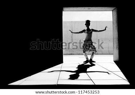 Dramatically lit photograph of woman dancing in a courtyard