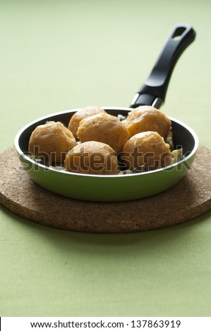 Close-up view of organic Chickpeas Falafel with Zucchini in a hot pan placed on a cork dish