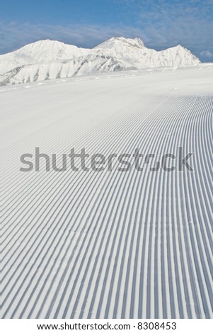 Tracks made by a snow grooming machine on a ski slope in the Alps.