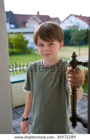 stock photo A preteen boy opens a door with his hand on the handle
