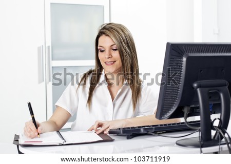 blond secretary with pen and computer in office