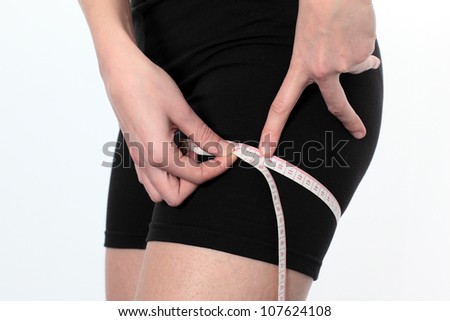 young woman measuring her thigh with a meter tape