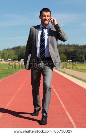 businessman with phone and laptop on a running track