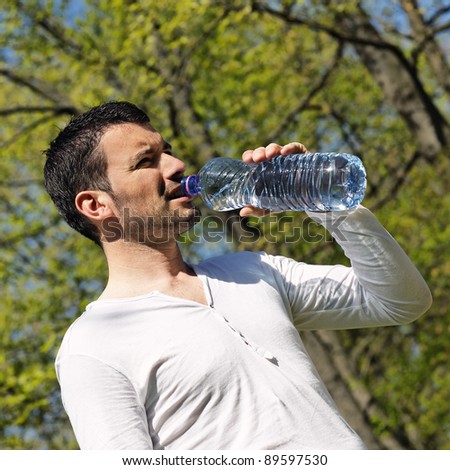 man drinking water after sport in a park