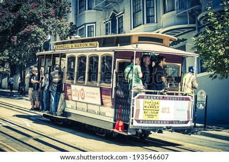 Powell Hyde cable car, an iconic tourist attraction, descends a steep hill overlooking Alcatraz prison and SF bay on October 6, 2012 in San Francisco, USA