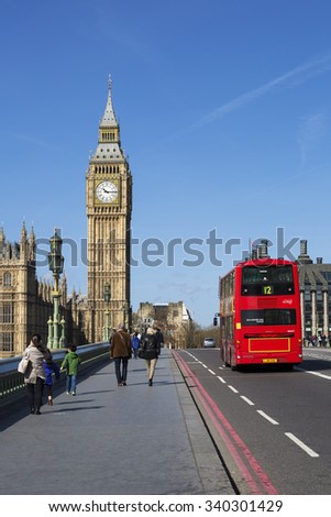 LONDON, UK - APRIL 12, 2015: double-decker bus passes pedestrians walking in front of Big Ben and Houses of Parliament on Westminster Bridge.