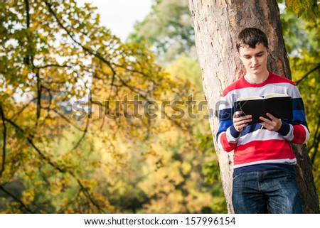 A young man reading a book in park