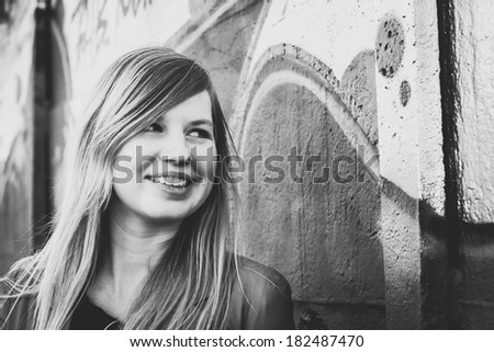 Beautiful young woman smiling at the graffiti wall