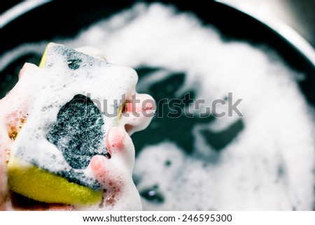 Young woman washing the pan with the yellow sponge