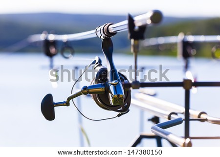 Fishing rods with fishing reels on tripod rack with blurred background