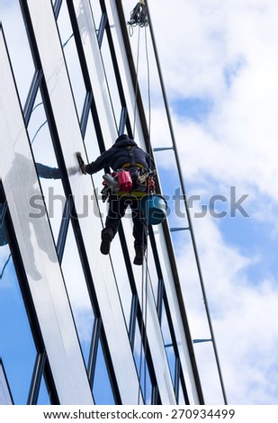 alpinist climber clean the windows of office building