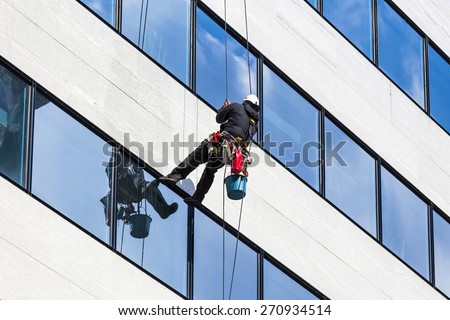 alpinist climber clean the windows of office building