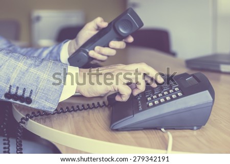 businessman dialing voip phone in vintage color effect