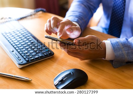 businessman use mobile phone in the office, mouse, pen and keyboard on the table
