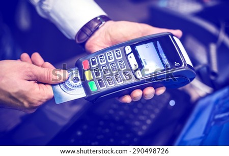 Payment with credit card - man put the credit card into a reader with blue color tone effect