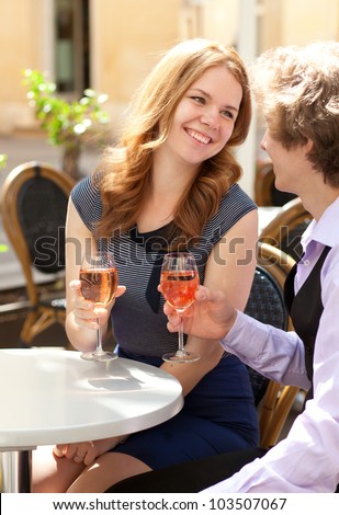 Beautiful couple having a date in a cafe and drinking rose wine