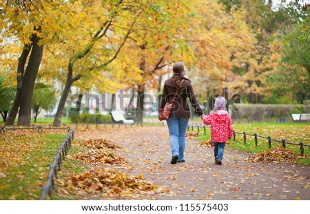 Mother and daughter walking together at beautiful autumn day