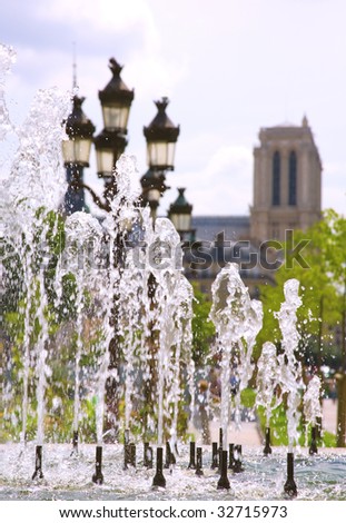 Summer in Paris. View of Notre-Dame de Paris through the fountain. Focus on the water jets