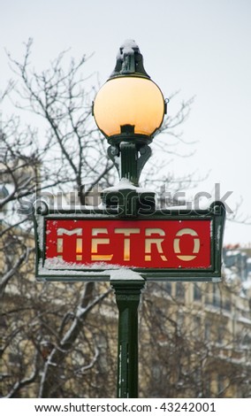 Rare snowy day in Paris. Parisian metro sign covered with snow