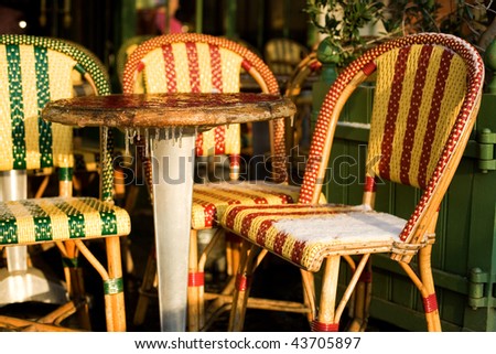 Rare snowy and cold day in Paris. Street cafe table and chairs covered with snow and ice